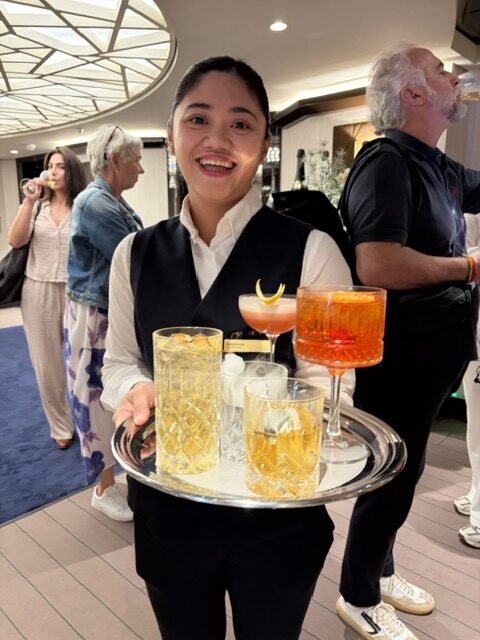 Servicemitarbeiterin mit Cocktail-Tablett lächelt